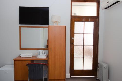 a room with a desk with a television and a door at Hurstville Ritz Hotel in Sydney