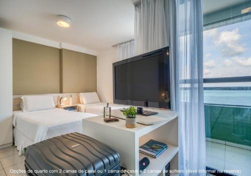 Habitación de hotel con TV grande y cama en Golden Tower en Natal