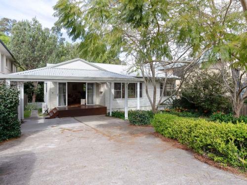 a white house with a porch and a driveway at Dutchies Haven, 11 Christmas Bush Ave - Pet friendly, large enclosed yard, air con and Wi-Fi in Nelson Bay