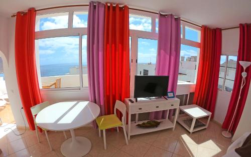 グラン・タラハルにあるApartamento junto el marの赤いカーテン、デスク、テレビが備わる客室です。