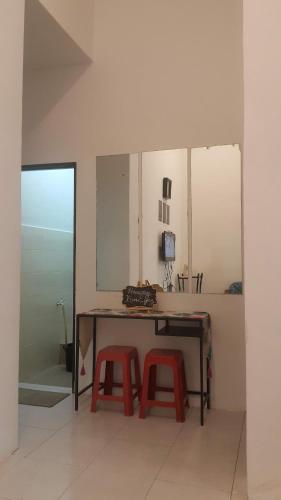 einen Schreibtisch mit zwei roten Hockern in einem Zimmer in der Unterkunft HOMESTAY EIJAZ KUALA ROMPIN in Kuala Rompin