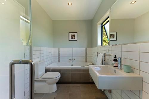 uma casa de banho com uma banheira, um WC e um lavatório. em The Cove at Little O em Oneroa