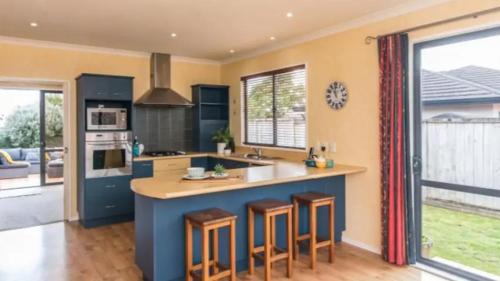 a kitchen with a blue island with bar stools at Quiet homestay, private room with own bathroom in Paraparaumu Beach
