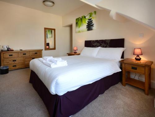 een slaapkamer met een groot wit bed en 2 tafels bij Stones Hotel and Bar in Minehead