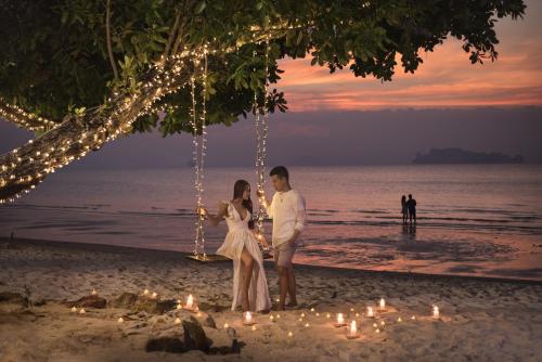 a couple standing on the beach with lights at Anyavee Tubkaek Beach Resort- SHA Plus in Tab Kaek Beach
