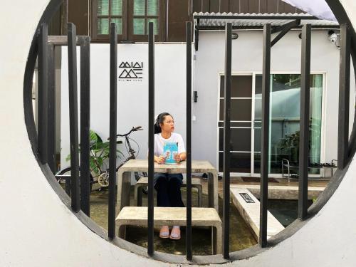a woman sitting at a table through a window at Mini-ME Home, A Cozy Entire House in Old City in Chiang Mai