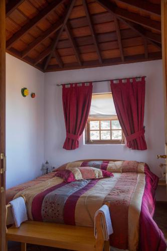 a bedroom with a bed with red curtains and a window at Casa Micaela in Garafía