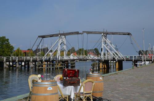 a bridge with a table and chairs in front of the water at Hotel zur Brücke in Greifswald