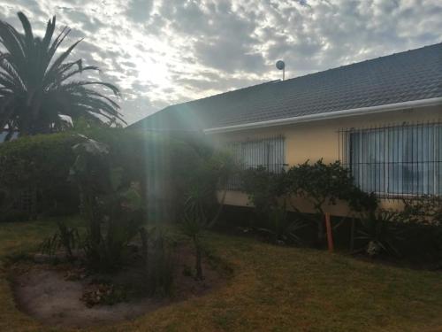 a house with a palm tree in front of it at Spacious 1bed + braai 13km to Paternoster beach in Vredenburg