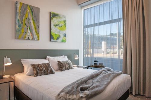 a bedroom with a large bed and a large window at Sojourn Apartment Hotel - Riddiford in Wellington