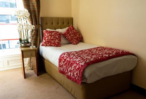 a bedroom with a bed with red pillows and a window at Brogans Bar & Hotel in Trim