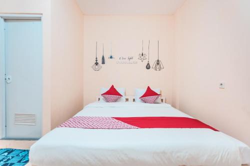 um quarto com uma grande cama branca com almofadas vermelhas em Super OYO 2034 Eden Guest House em Depok