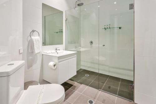 a white bathroom with a toilet and a shower at Meridian Hotel Hurstville in Sydney
