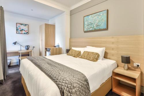 a bedroom with a large bed and a desk at Meridian Hotel Hurstville in Sydney