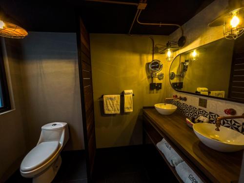 a bathroom with two sinks and a toilet and a mirror at Cadillac Hotel Boutique in Mexico City