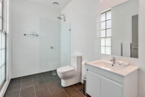 a white bathroom with a toilet and a sink at Meridian Hotel Hurstville in Sydney