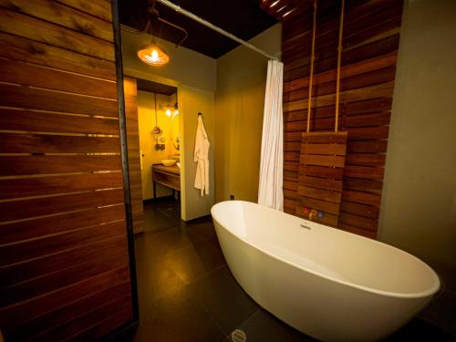 a bathroom with a large white tub and wooden walls at Cadillac Hotel Boutique in Mexico City