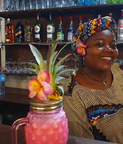 a woman standing in a bar with a vase with a drink at Hotel ECOLODGE LE RAVORAHA in Sainte Marie