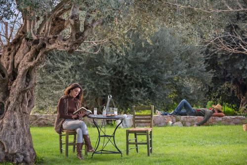 a woman sitting at a table under a tree at Agroktima in Leonidion