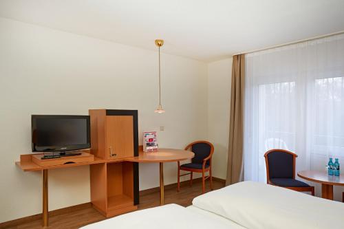 a room with a desk with a tv and a table with chairs at Micador Appartementhaus in Niedernhausen