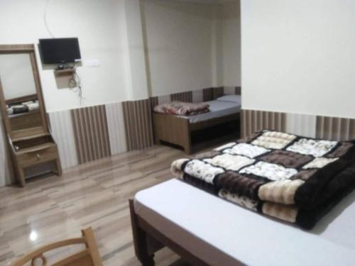 a room with a bed and a table in a room at Maa Anand Mayee Guest House in Panuānaula