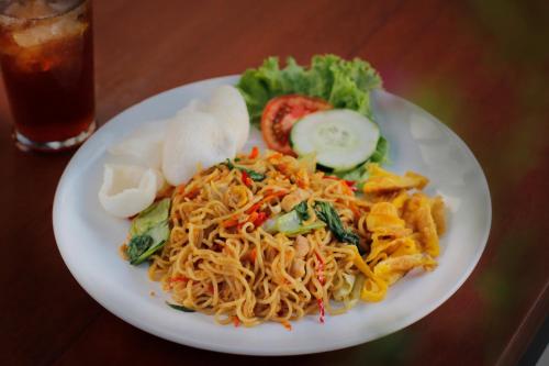 a plate of food with noodles and vegetables on a table at Bingin Lodge Uluwatu in Uluwatu