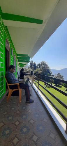 two men sitting on a bench on a balcony at Maa Anand Mayee Guest House in Panuānaula