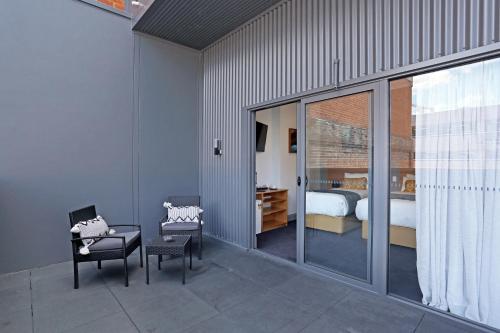 a room with a bedroom with a bed and chairs at Meridian Hotel Hurstville in Sydney