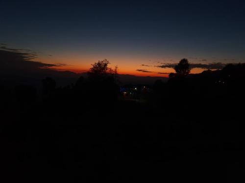 a sunset in the sky with trees in the foreground at Maa Anand Mayee Guest House in Panuānaula