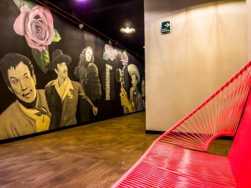 a red bench in a room with a mural at Cadillac Hotel Boutique in Mexico City
