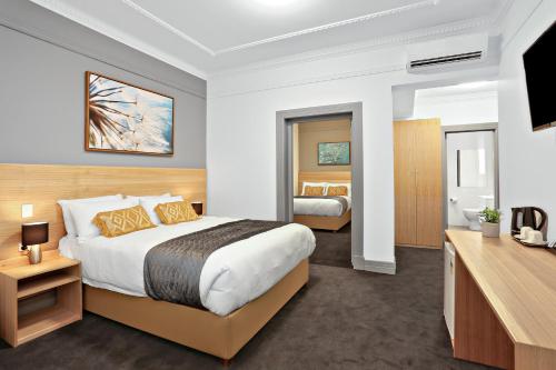 a hotel room with a bed and a television at Meridian Hotel Hurstville in Sydney