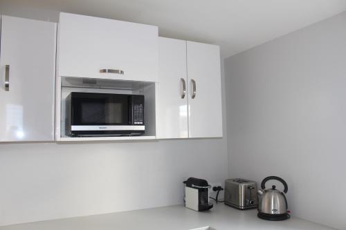 a kitchen with white cabinets and a microwave at Blue Skies Guest Accommodation in Queenstown