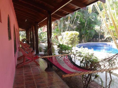una hamaca en el porche de una casa con piscina en Hotel El Paraiso Escondido - Costa Rica, en Jacó