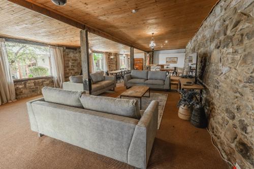 a living room with couches and a stone wall at Penwarn Farm Lodge in Drakensberg Garden