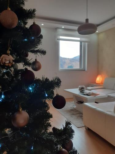 ein Weihnachtsbaum im Wohnzimmer mit Sofa in der Unterkunft Apartman Teodora in Kopaonik