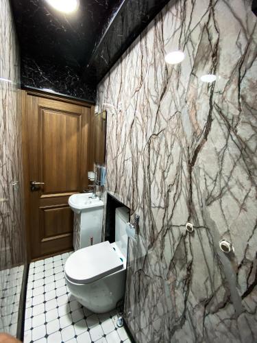 a bathroom with a toilet and a marble wall at BUDGET HOTEL and HOSTEL in Tashkent