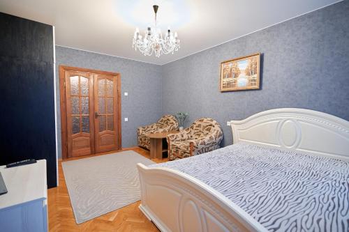 a bedroom with a white bed and a chandelier at Holiday and Travel Apartment in Brest