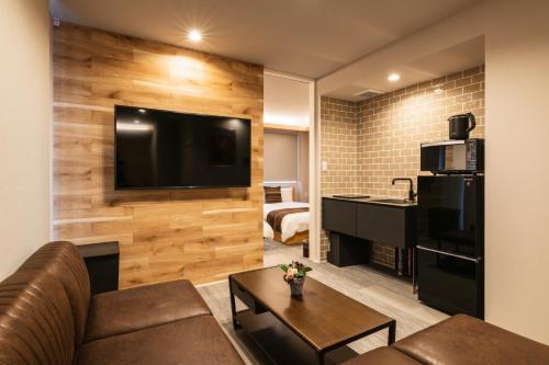 a living room with a couch and a tv on a wall at GRAND BASE Urakami in Nagasaki