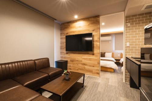 a living room with a couch and a television on a wall at GRAND BASE Urakami in Nagasaki