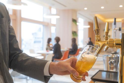 a person holding a glass of beer at a bar at ibis Styles Osaka Namba in Osaka
