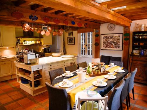 cocina con mesa larga y sillas en Villa de 6 chambres avec piscine privee jardin amenage et wifi a Gonneville sur Mer a 4 km de la plage en Gonneville-sur-Mer