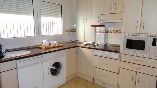 a kitchen with white cabinets and a washer and dryer at 4 bedrooms house with terrace at Aldea Real in Aldea Real