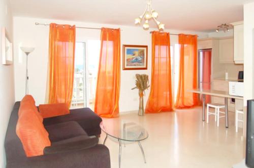 a living room with orange curtains and a couch at 2 bedrooms apartement at Palm Mar 800 m away from the beach with sea view shared pool and furnished terrace in Palm-Mar