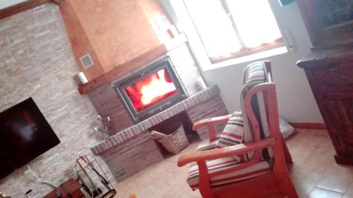 - un salon avec une cheminée en briques et une chaise dans l'établissement 3 bedrooms house with enclosed garden at Peral de Arlanza, à Peral de Arlanza