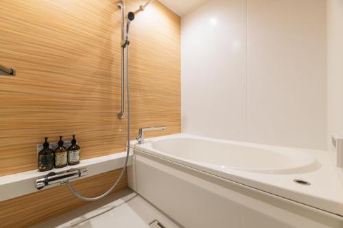 a bathroom with a bath tub and a sink at GRAND BASE Urakami in Nagasaki