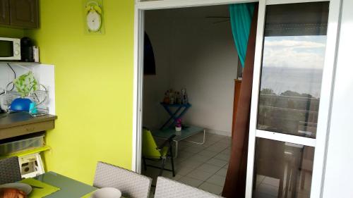 a kitchen with a door open to a room with a table at Appartement moderne à Sainte-Anne 43 m² avec vue mer in Sainte-Anne