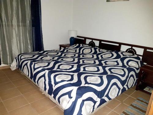 a bed with a black and white comforter in a bedroom at One bedroom appartement with furnished garden and wifi at La Savane 2 km away from the beach in Happy Bay