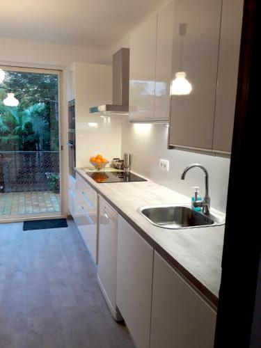 une cuisine avec des armoires blanches et un évier dans l'établissement Maison charmante à Sainte-Marie avec grand jardin, à Sainte-Marie-la-Mer