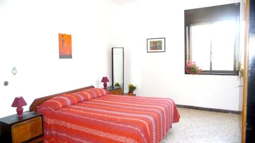 a bedroom with a bed with a red blanket and a window at 4 bedrooms house with furnished terrace and wifi at Marinella di Selinunte 1 km away from the beach in Marinella di Selinunte