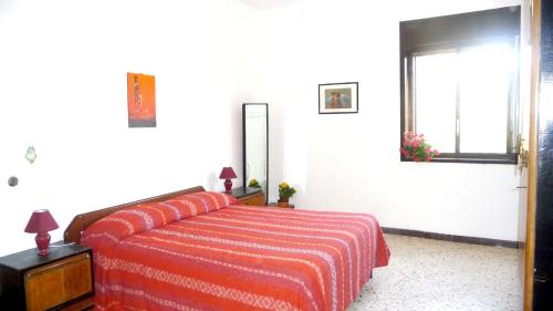 マリネッラにある4 bedrooms house with furnished terrace and wifi at Marinella di Selinunte 1 km away from the beachのベッドルーム1室(赤毛布、窓付)